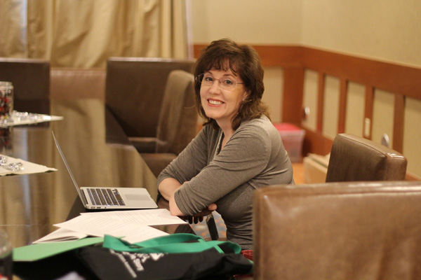 Janette Rallison at a table with her computer and pages of writing.